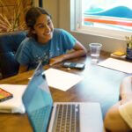 Smiling student engaged in a tutoring session at Study Hut, surrounded by school supplies, a laptop, and a calculator in a bright, supportive learning environment.