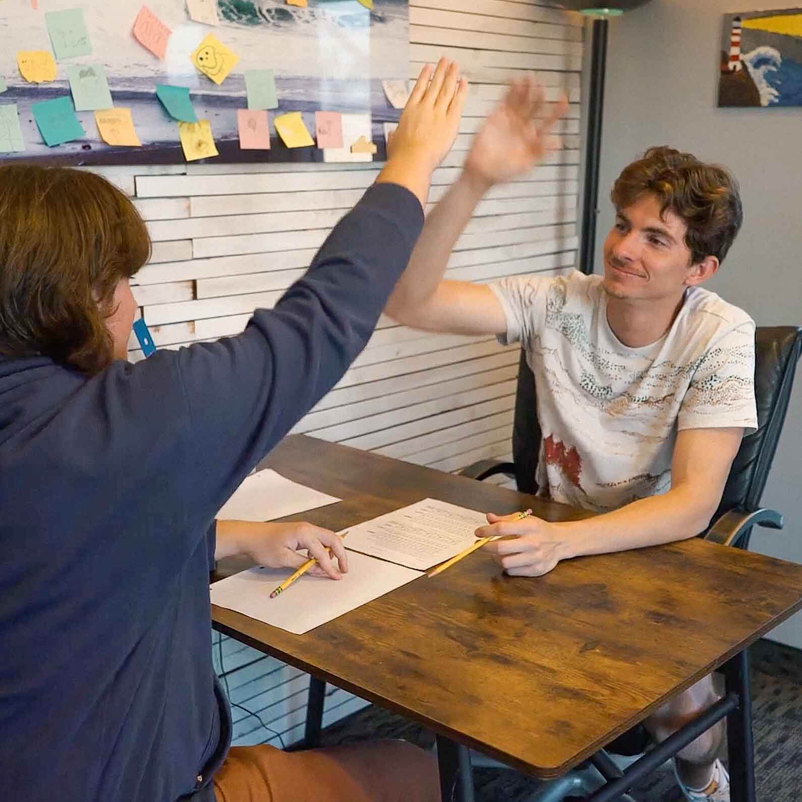 Tutor and student celebrate a successful tutoring session with a high five at Study Hut, showcasing a fun and encouraging learning environment.